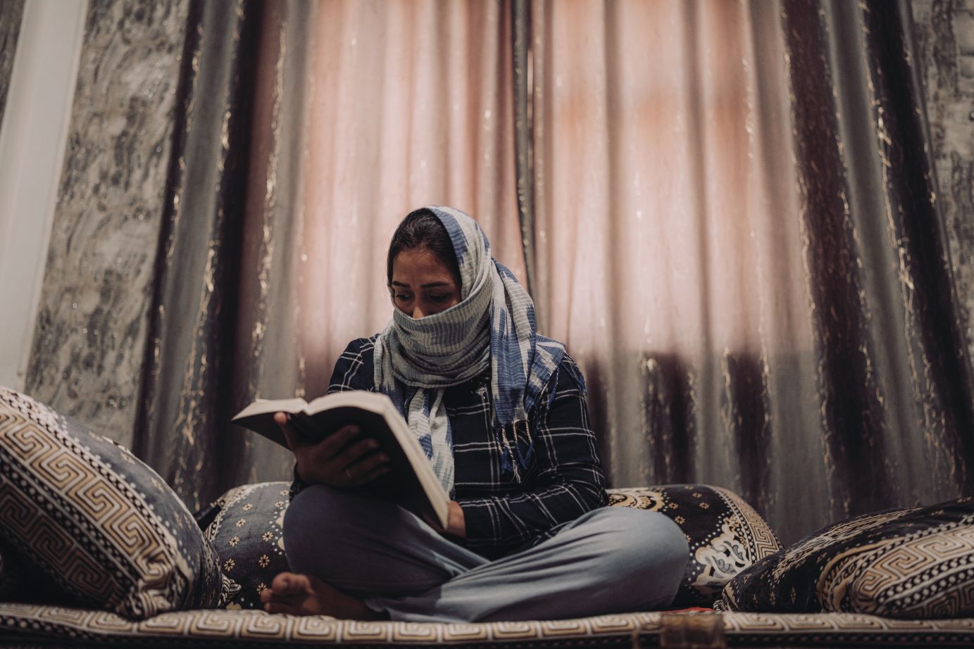 Žena se šátkem čte Bibli.