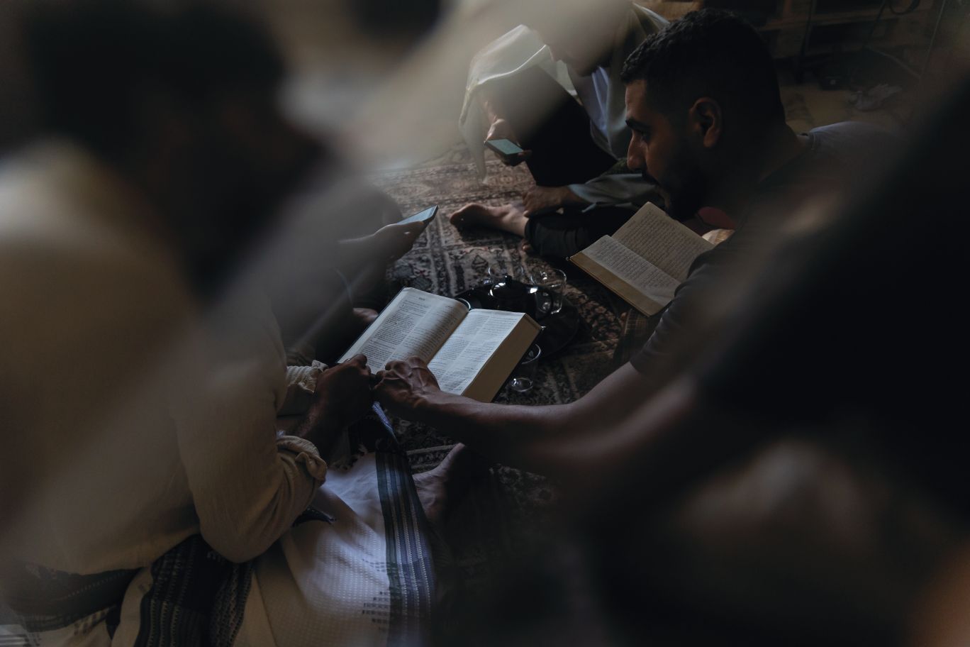 Muži na zemi čtou Bibli.